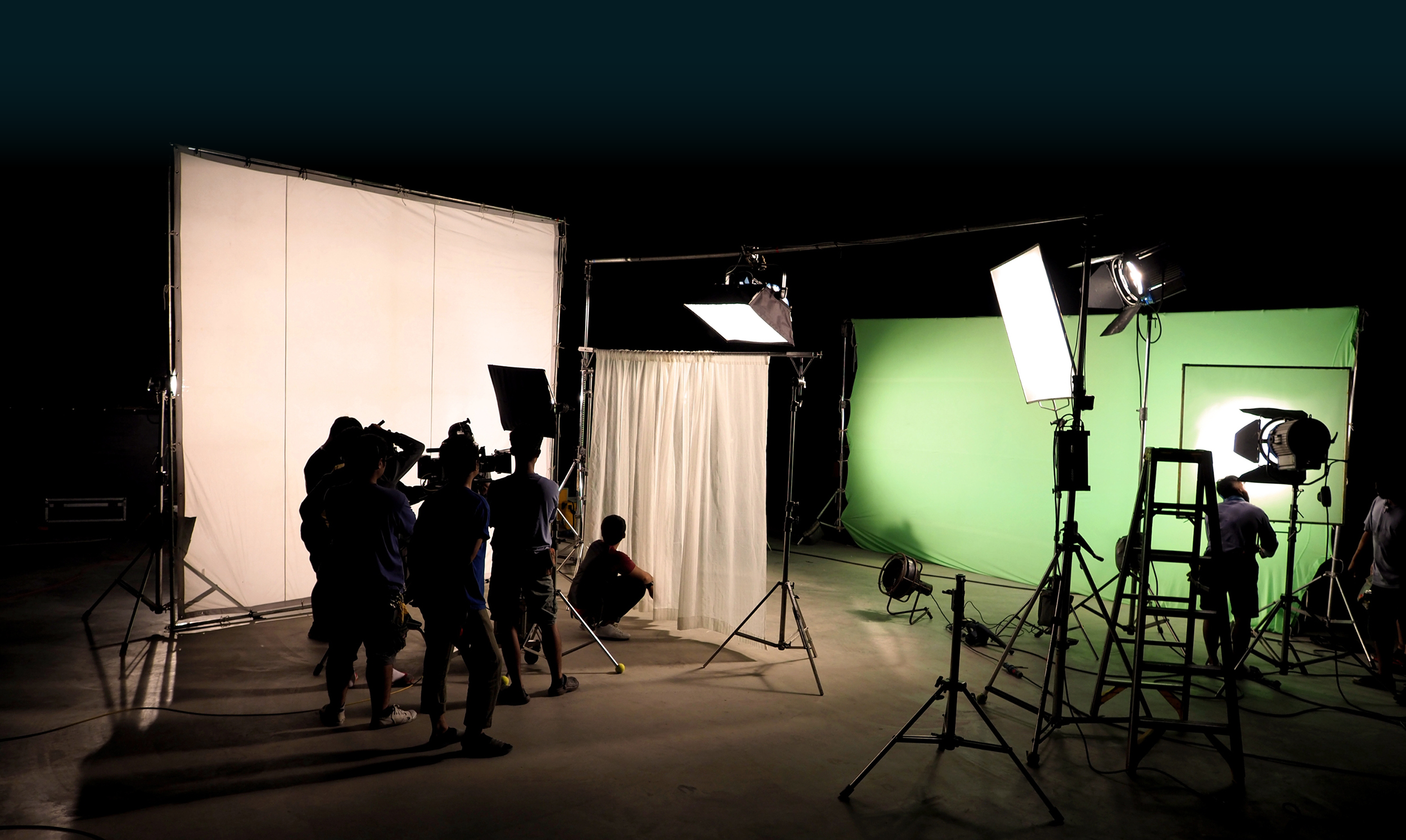 Iluminación de silueta de escena en la que el equipo de filmación está configurando la cámara y preparando el rodaje