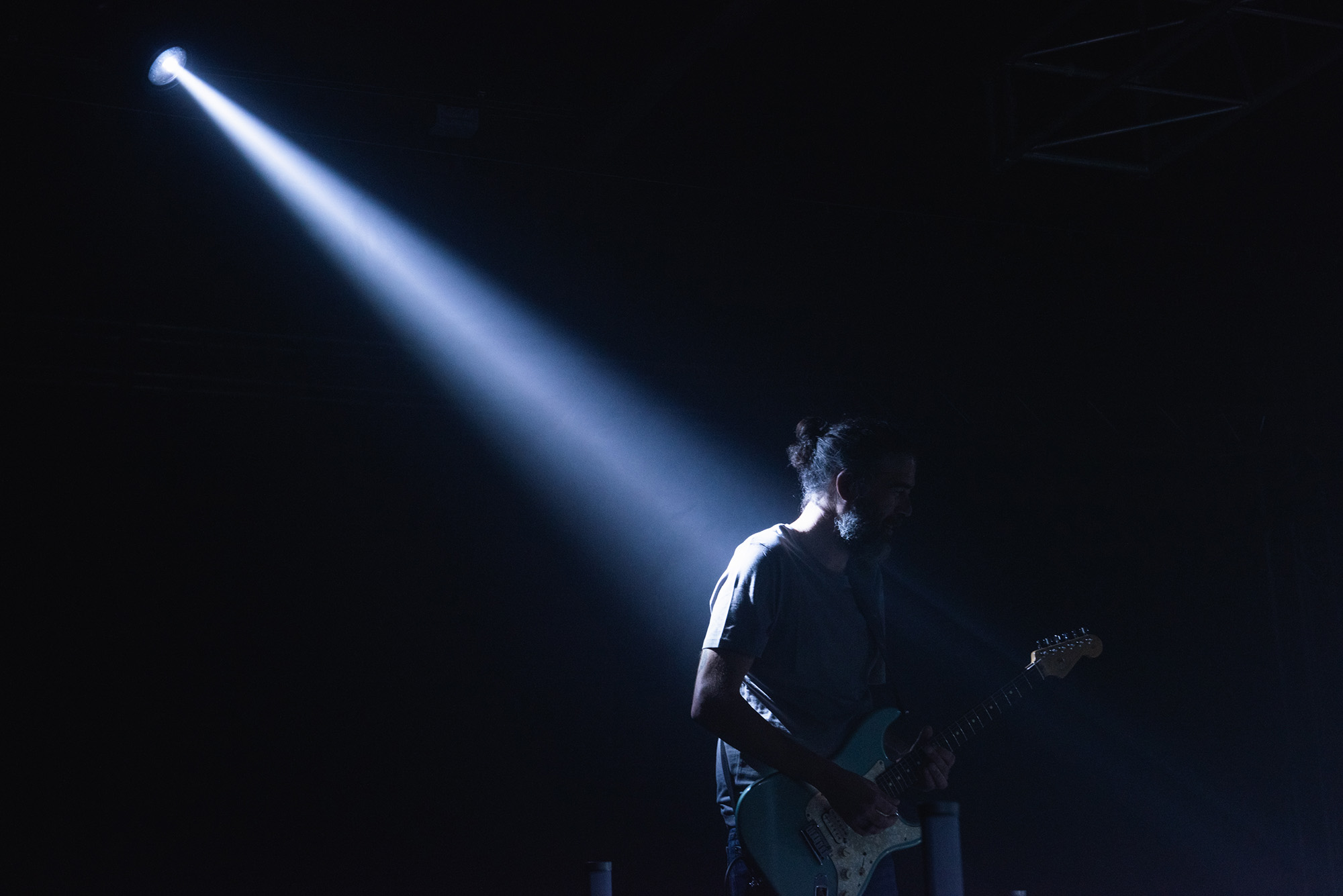 Guitarrista tocando a oscuras con un foco de luz sobre él