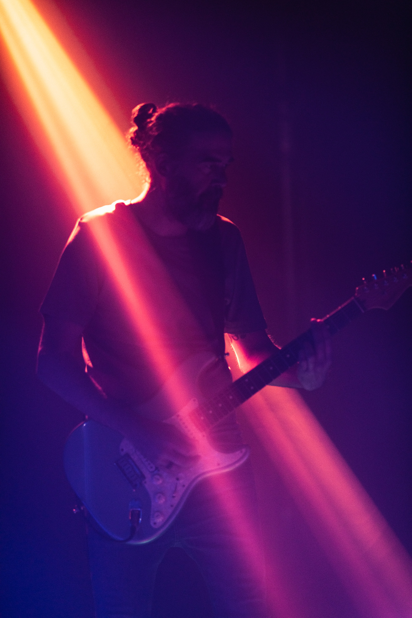 Guitarrista tocando a oscuras con un foco de luz cálida sobre él