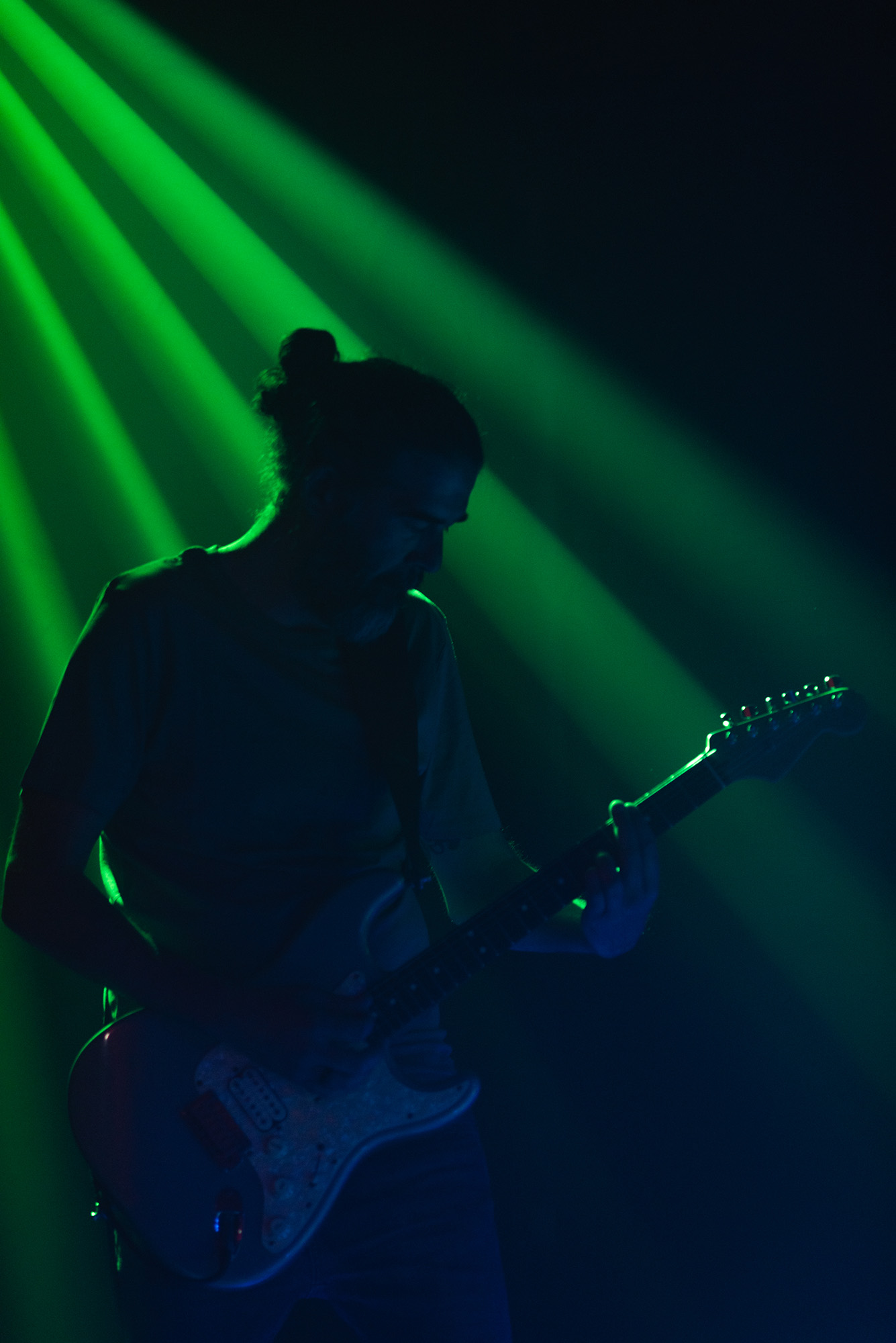 Guitarrista tocando a oscuras con un foco de luz verde sobre él