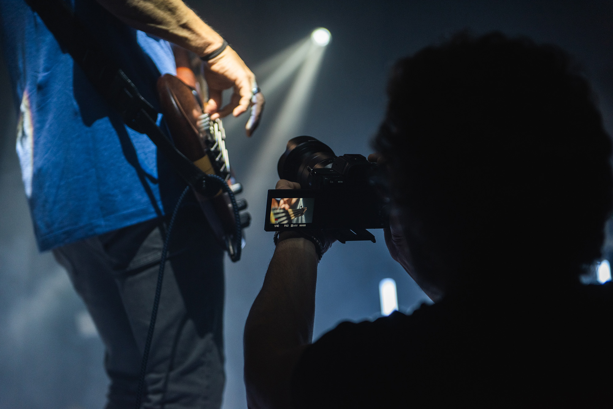 Guitarrista tocando mientras un videografo graba las manos en las cuerdas